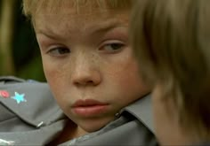 a young boy with freckles on his face looking at another child's face