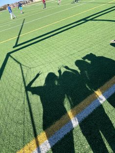 the shadow of two people on a soccer field with their shadows cast by a goalie's net