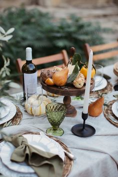 a table set with plates, wine glasses and other items for an outdoor dinner party