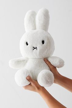 a hand holding a white stuffed animal with black eyes and an angry look on its face