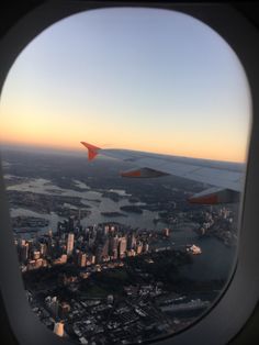 an airplane window looking out at the city and water from inside it's plane