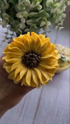 a yellow flower sitting on top of a wooden table