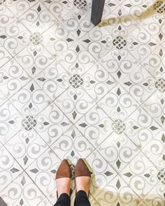 a person standing on a tiled floor with their feet propped up in front of them