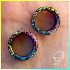 two small colorful beads sitting on top of a person's hand with a skull in the background