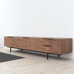 a wooden dresser sitting on top of a hard wood floor next to a white wall