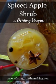 a drink with an orange garnish in it and the words spiced apple shrub