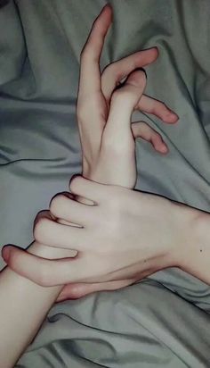 two hands touching each other on a bed