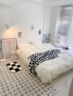 a white bed sitting in a bedroom next to a black and white checkered rug