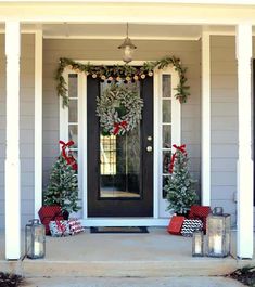 two christmas wreaths on the front door of a house