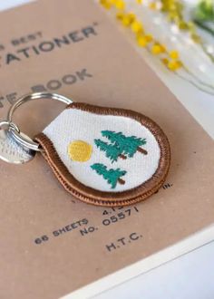 a keychain with a small embroidered tree on it