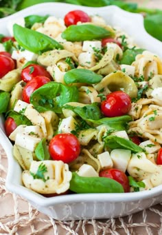 a white bowl filled with pasta salad and veggies on top of a table