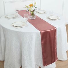 the table is set with white and pink linens, silverware, and flowers