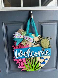 a welcome sign hanging on the front door with sea life and turtle decorations around it