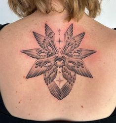 the back of a woman's shoulder with a tattoo design on it, and a cross in the center