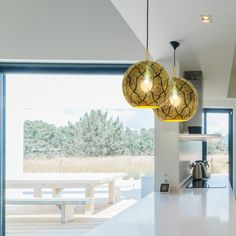 two lights hanging over a kitchen counter next to a large open window with an outside view