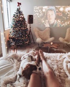 a woman laying on top of a fluffy rug next to a christmas tree and a tv