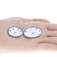 two small white and blue dishes in the palm of a person's hand,