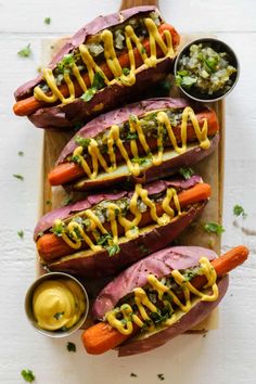 three loaded hot dogs with mustard drizzled on them