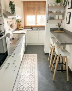 a kitchen with white cabinets and gray flooring next to a counter top oven, sink, microwave and dishwasher