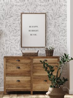 a wooden dresser sitting next to a plant in a room