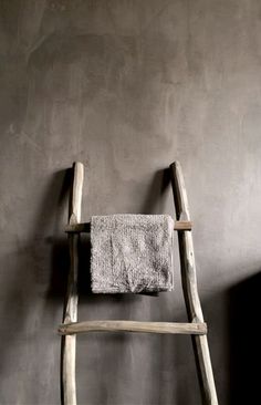 an old wooden ladder leaning against a wall with a towel hanging on it's side