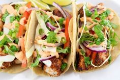 three tacos with meat, onions and lettuce are on a white plate