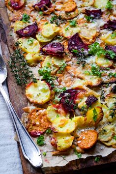 a wooden cutting board topped with a pizza covered in veggies