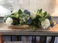 a vase filled with white and blue flowers on top of a table