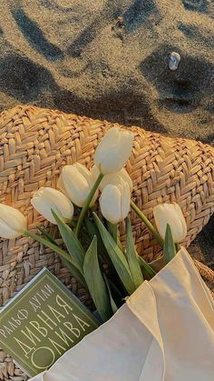 some white tulips and a book on the sand