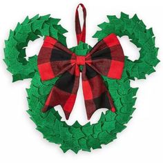 a green wreath with red and black plaid bow hanging from it's side on a white background