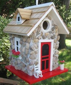 a birdhouse made out of rocks and wood with a red door on the side