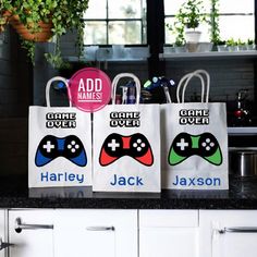 three bags with video game controllers on them are sitting on a kitchen counter next to a potted plant