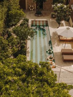 an aerial view of a swimming pool with lounge chairs and umbrellas