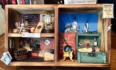 an open wooden box filled with assorted items on top of a wood table next to a pile of books