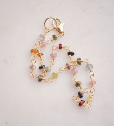 Spread creativity and joy with this multicolor gemstone Tourmaline bracelet! This handmade beauty features natural Tourmaline crystals in a variety of hues, including pink, black, green, and yellow. Each bracelet is unique, with no set pattern, making each one a one-of-a-kind. It comes in your choice of sterling silver or 14k gold filled. Tourmaline Meaning: The birthstone for October, Tourmaline is believed to promote inspiration, boost confidence, and combat fear. Stone Size: Average 3-4mm Mat Gold Bracelets With Natural Stones And Tourmaline, Gold Tourmaline Bracelets With Natural Stones, Gold Tourmaline Gemstone Bracelets, Multicolor Wire Wrapped Bracelet, Spiritual Multicolor Tourmaline Beaded Bracelets, Multicolor Tourmaline Bracelet Jewelry, Dainty Multicolor Gemstone Beads Bracelets, Multicolor Tourmaline Bracelet, Dainty Multicolor Gemstone Bracelet