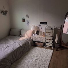 a small bedroom with a bed, dresser and mirror in the corner next to it