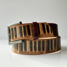 This beautiful belt is handmade  from 100% genuine vegetable tanned leather I used an antique dye to and distressed the edges to give it a vintage look.  It features a printed design based on an old piano keyboard. The belt is finished with a distressed single-loop buckle. 🌟 Lovingly handcrafted by ️ in myUK home studio. There may be small variations compared to the listed pictures, but that's part of the charm! - No two items are  exactly the same :)  Width: 38mm Thickness: Approx. 3-3.5mm Cool Belt, Handmade Belt, Old Pianos, Handmade Belts, Piano Keyboard, Belt Vintage, Beautiful Belts, Gift For Music Lover, Suspender Belt