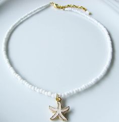 Starfish Choker Sea Choker White Choker Necklace White Beaded Choker Summer Jewelry Beach Necklace Dainty and elegant all white beaded choker with glass tiny seed beads and a white enameled starfish charm. DESCRIPTION Made from 2mm glass seed beads and closes with a gold plated clasp and 2 inches adjustable chain. SIZE Necklace is 13 inches and can be adjusted up to 15 inches with a 2 inches extender chain. Please let me know if you would like a different length. WRAPPING - All ZafireniaDainty j White Star-shaped Ocean-inspired Jewelry, Ocean-inspired White Star Jewelry, Ocean-inspired White Star-shaped Jewelry, White Star-shaped Jewelry With Starfish Charm, White Starfish Pendant Ocean-inspired Jewelry, White Jewelry With Star Charm And Round Beads, White Beaded Necklaces With Starfish Charm For Beach, Ocean-inspired Starfish Charm Beaded Necklace, White Ocean-inspired Jewelry With Starfish Charm