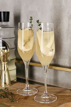 two champagne glasses with lemon and rosemary garnish sitting on a wooden counter top