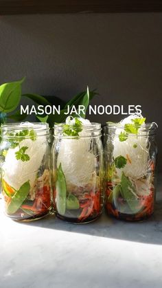 mason jar noodles with vegetables and herbs in them sitting on a counter top