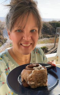 a woman is smiling while holding a plate with food on it and looking at the camera