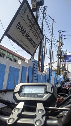 there are many motorcycles parked next to each other on the side of the street with signs above them