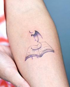 a person with a book tattoo on their arm