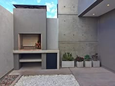 an outdoor fireplace in the middle of a concrete courtyard with potted plants and gravel