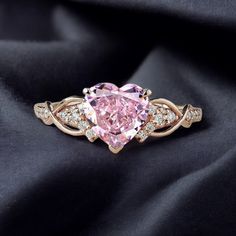 a fancy pink diamond ring sitting on top of a black cloth