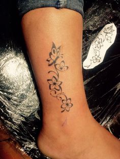 a woman's foot with a tattoo design on the side of her leg,