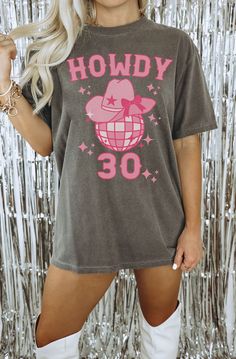 a woman posing in front of a tin foil backdrop wearing a t - shirt with the number 30 printed on it