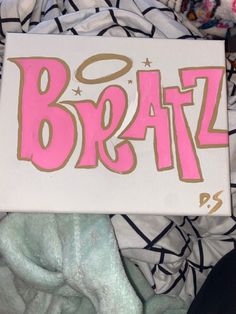 a sign that says braz on it in pink and gold lettering, sitting next to some blankets