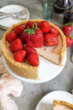 there is a cheesecake with strawberries on the top and one slice missing from it