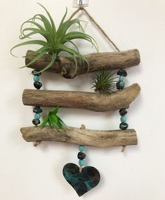 an air plant hanging from a wooden branch with beads and glass bead necklaces